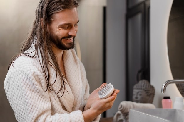 A man applying pre-shave oil to his face, focusing on the beard area. His fingers are gently massaging the oil into the skin, and the background shows a blurred bathroom setting.