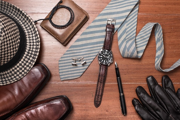 An array of men's accessories, including watches, belts, ties, and sunglasses, arranged on a wooden surface, showcasing the various options available to enhance a man's style.