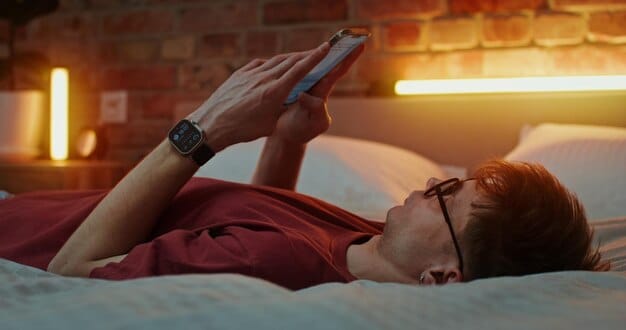 A man using a meditation app on his phone in bed, with blue light filtering glasses on, illustrating the integration of technology and mindfulness for better sleep.