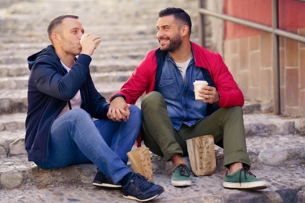 Two men sitting side-by-side, engaged in a serious, supportive conversation, in a relaxed outdoor setting.