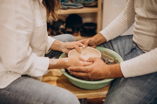 A group of people laughing and working together in a pottery class, their hands covered in clay, showcasing teamwork and shared creativity.