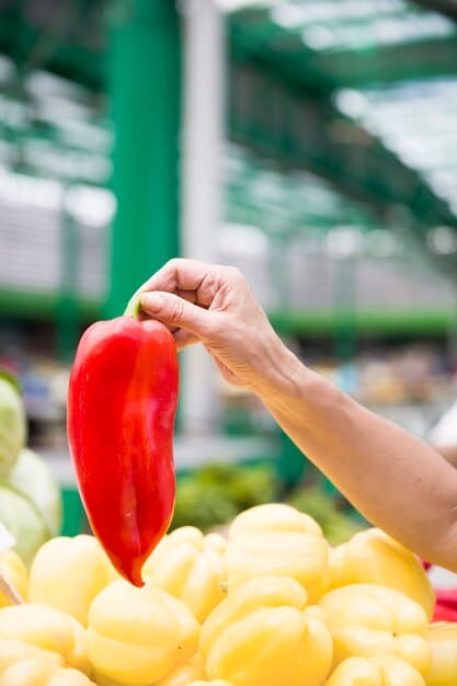 A close-up image of a person's hand selecting fresh vegetables from a market stall, emphasizing the importance of choosing healthy foods for overall well-being, including sexual health. The colors are vibrant and inviting, showcasing a variety of nutritious options.