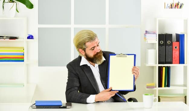A person meticulously organizing folders and documents on a laptop, with a whiteboard in the background filled with productivity metrics and project timelines, representing detailed achievement tracking.