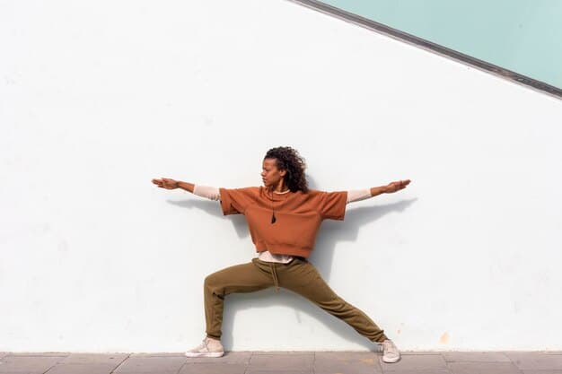 A person performing Wall Angels against a plain wall, demonstrating good form with arms extended upwards, smiling slightly, showcasing an accessible exercise.