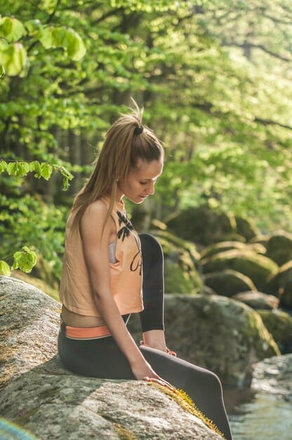 A person stretching or meditating calmly after a workout, surrounded by nature, conveying a sense of flexibility, recovery, and peaceful resilience in their fitness journey.