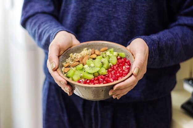 A person's hands holding a vibrant salad bowl filled with diverse vegetables, fruits, and nuts, depicting conscious and prepared healthy eating.