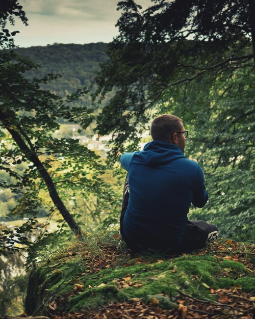 A man in a serene setting, possibly a nature trail, contemplating with a thoughtful expression, representing introspection and a mindful approach to life.