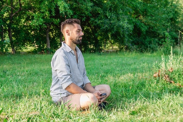 A man sitting calmly in a park, meditating, signifying emotional regulation and peaceful processing.