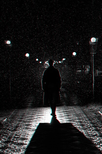 A silhouette of a man stands alone on a city street at dusk, surrounded by blurred lights, symbolizing loneliness and being lost in a crowd.