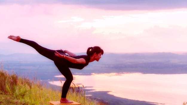 A person performing a yoga pose at sunrise, illustrating balance, flexibility, and a mindful approach to physical well-being.