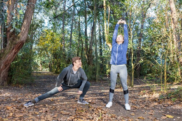 A man exercising outdoors, perhaps jogging, with a woman stretching beside a tree, emphasizing active lifestyle and diabetes management to prevent ED.