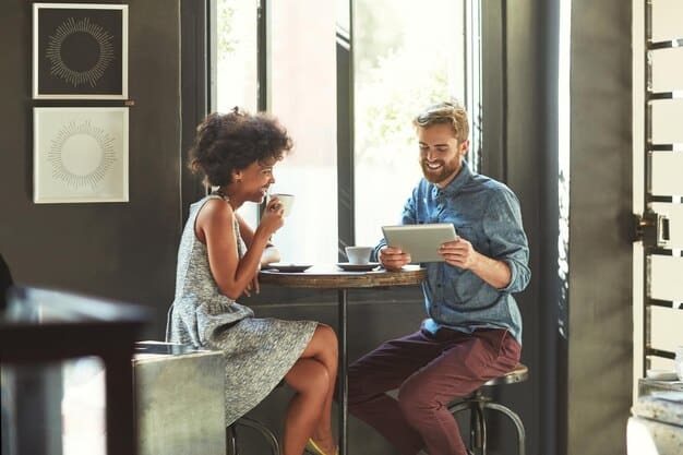 Two professionals having a relaxed conversation over coffee. The setting is a modern café, and they are both smiling and engaged in the discussion. This represents building relationships and camaraderie.