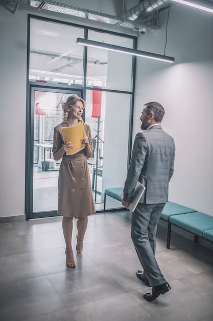 Two colleagues standing in an office hallway, having a private, tense conversation. Their body language suggests disagreement and frustration, but they are attempting to communicate. This image vividly represents the everyday reality of How to Handle Workplace Conflict: Resolve Issues Professionally and Maintain Positive Relationships in a professional setting.