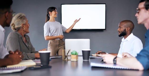 A diverse group of professionals collaborating in a modern office, pointing at a presentation screen displaying the words 