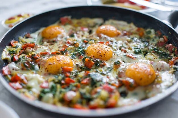 A close-up shot of a skillet filled with colorful scrambled eggs mixed with spinach, diced tomatoes, and sliced mushrooms. The eggs are cooked to a soft, fluffy texture, and the vibrant colors of the vegetables are clearly visible, highlighting the dish's nutritional value and visual appeal as part of 7 High-Protein Breakfast Ideas to Fuel Your Day.