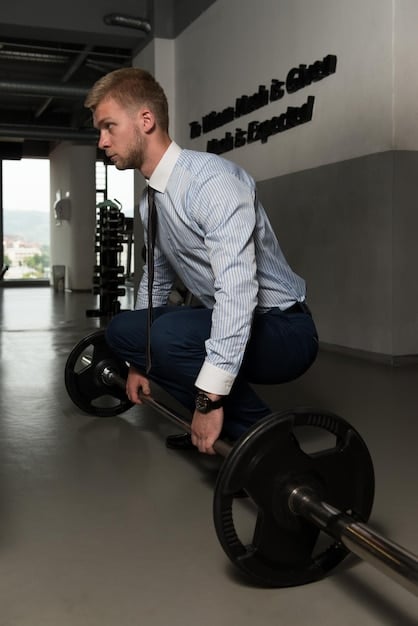 A man grimacing while lifting a weight with a rounded back during a deadlift. His form is clearly incorrect and demonstrates a common gym mistake. The background is a typical gym setting with weights and equipment.