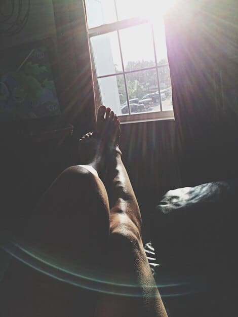 A man sleeping peacefully in bed, with sunlight streaming through the window. The scene conveys rest and recovery, a crucial aspect of a balanced fitness routine. He's relaxed and comfortable.