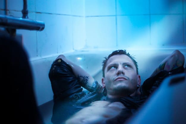 A man sitting in a cryotherapy chamber, surrounded by vapor, with a focused expression. The setting is a modern wellness center, emphasizing the high-tech recovery aspect of The Best Post-Workout Recovery Strategies for Men in 2025.
