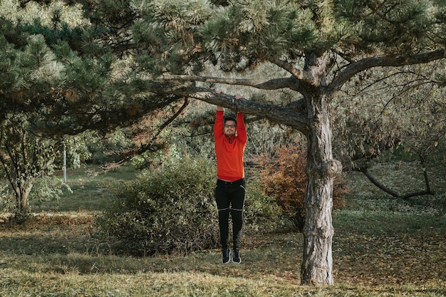 A man standing outdoors, looking at a tree. He is using the 5-4-3-2-1 grounding technique, a crucial part of Mindfulness for Men: 5 Simple Exercises to Reduce Stress in Under 10 Minutes, to connect with his surroundings and reduce anxiety. The scene is natural and calming.