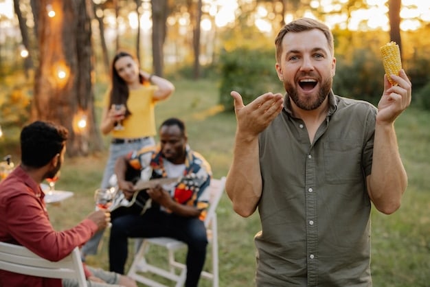 A smiling man laughing with friends outdoors at a picnic in the sunshine, away from screens and technology, celebrating newfound real-world social connections facilitated by regularly partaking a Digital Detox: How Limiting Screen Time Can Boost Men's Mental Wellbeing.