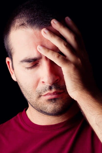 A close-up of a man's face, showing signs of fatigue and strain. His eyes are bloodshot, and he has dark circles under them. He's sitting at a computer, but his expression is one of disinterest and exhaustion, reflecting the challenges of 'How to Identify the 5 Early Warning Signs of Burnout in Male Professionals (and What to Do in 2025)'.