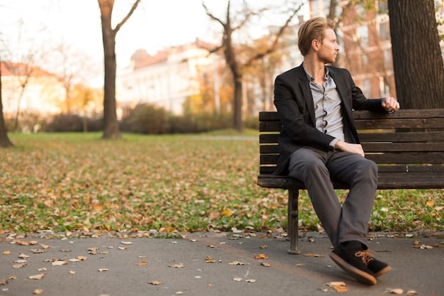 A man sitting alone on a park bench, looking thoughtfully at the ground. The scene is in grayscale to emphasize the feeling of loneliness and introspection, illustrating the challenges of isolation discussed in 'Combatting Loneliness and Isolation: Practical Strategies for Improving Social Connections for Men in the US'. The park should be somewhat empty and the man dressed in casual attire.