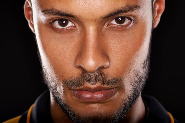 A close-up shot of a man's face, his brow furrowed in concentration as he stares intensely at a computer screen. The lighting is stark, highlighting the tension in his face, symbolizing the intense focus required in high-pressure jobs. This visually represents workplace stress.