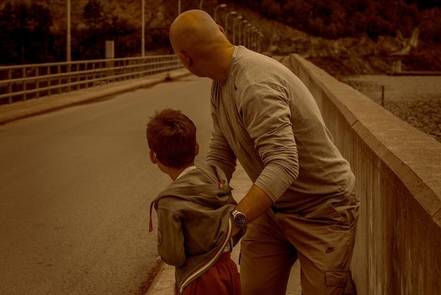 A close-up image showcasing a father and son in deep conversation while walking together in a park, with the father listening attentively and displaying empathy. The scene symbolizes a supportive and open dialogue between generations about mental health, highlighting the importance of family support in breaking the stigma.