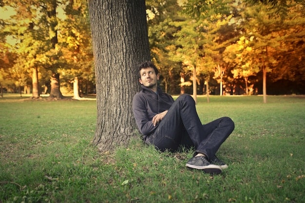 A man sitting alone in a peaceful setting, such as a park or garden, practicing mindfulness or meditation. His eyes are closed, and he appears calm and relaxed. The scene evokes a sense of tranquility and introspection, highlighting the importance of mindfulness in Understanding and Managing Anger Issues in Men: Effective Strategies for Emotional Regulation.