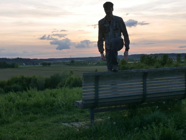 A landscape image showing a solitary figure, representing a male veteran, standing at the edge of a vast, open field with a stormy sky above. The image captures the feeling of isolation and inner turmoil often associated with mental health challenges faced post-military service, emphasizing the need for 'Understanding the Unique Mental Health Challenges Faced by Male Veterans: Resources and Support'.