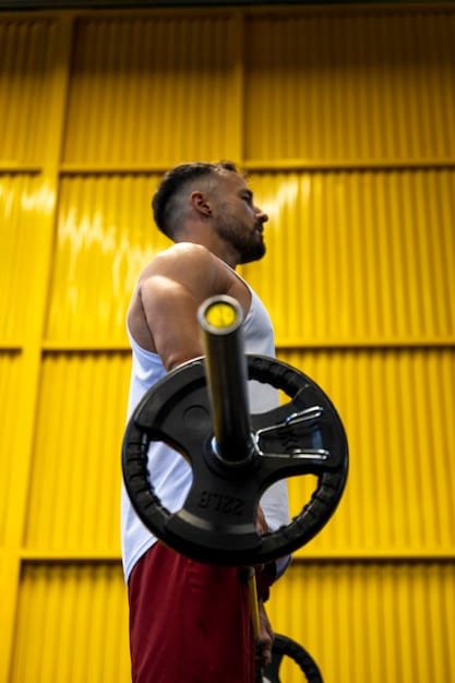 A man is lifting weights in a gym, focused, with good form. This image represents physical activity as a form of self-care and stress relief. It should visually connect to 'The Importance of Self-Care for Men: Practical Tips for Prioritizing Your Mental Health' by demonstrating a proactive approach to mental well-being through exercise.