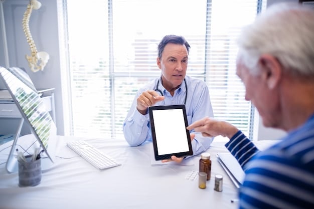 A doctor is explaining the process to the patient using a tablet. A penile implant is seen on the table.