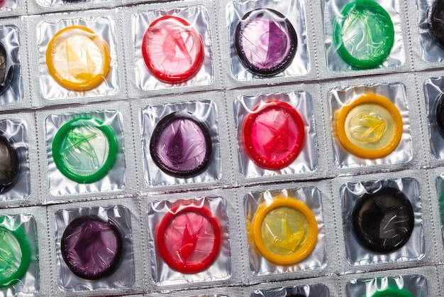 A close up shot of different types of condoms showing the textures in condoms like ribbed or dotted, highlighting the increased stimulation for both partners during sex.